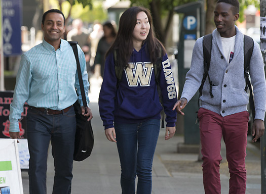 two young men and young woman walking along sidewalk